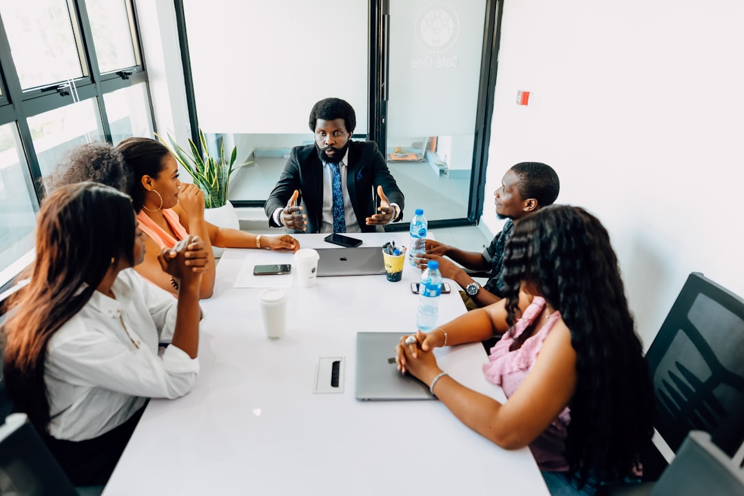 A group of people are sitting around a table in a meeting room. Find more afro-centric images at www.ninthgrid.com